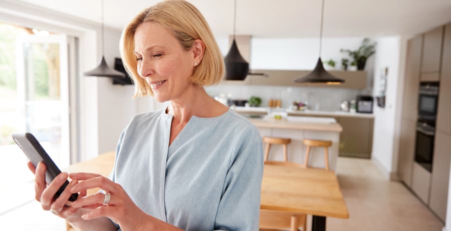 Resident holding a mobile device in a room filled with sunlight